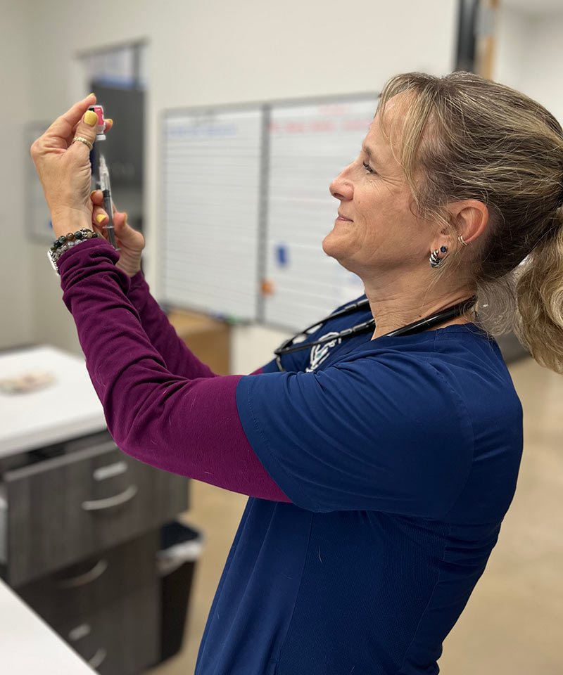 veterinarian smiling and preparing a vaccine at Liberty Hill Veterinary Wellness