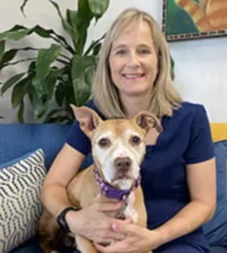 Blonde woman holding tan dog.